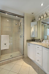 A bathroom with a glass walk-in shower and white cabinetry