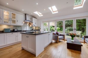 Modern furnished kitchen with island, seating, and bifold doors leading to patio garden
